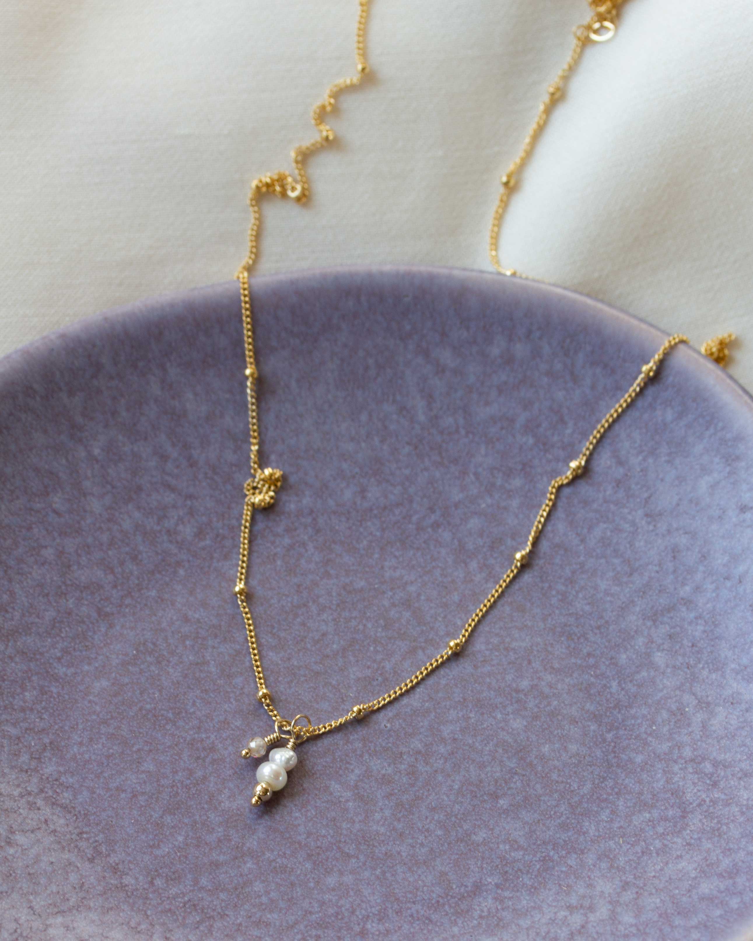 paars bordje met gouden ketting en parelhanger