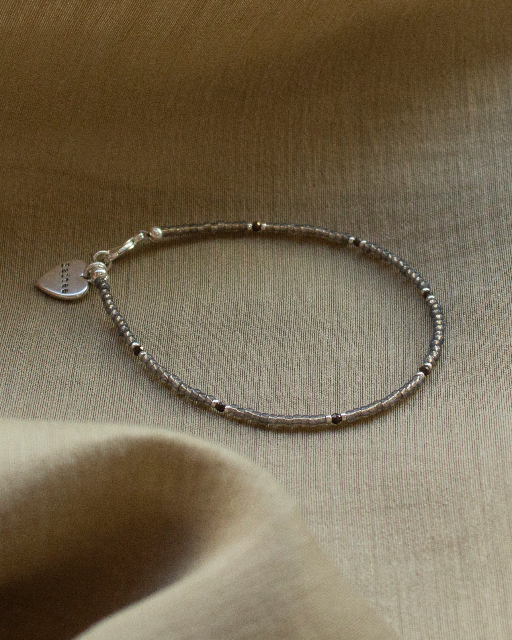 fijn grijsbruin kralenarmbandje met hartjesbedel