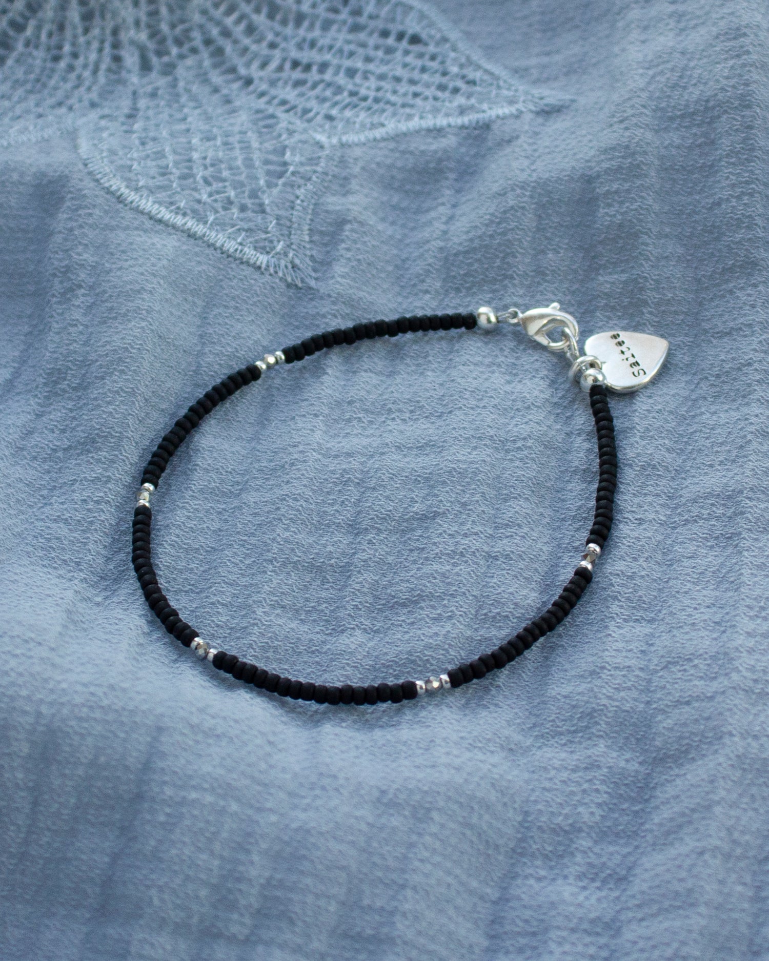 fijn mat zwart kralenarmbandje met hartjesbedel