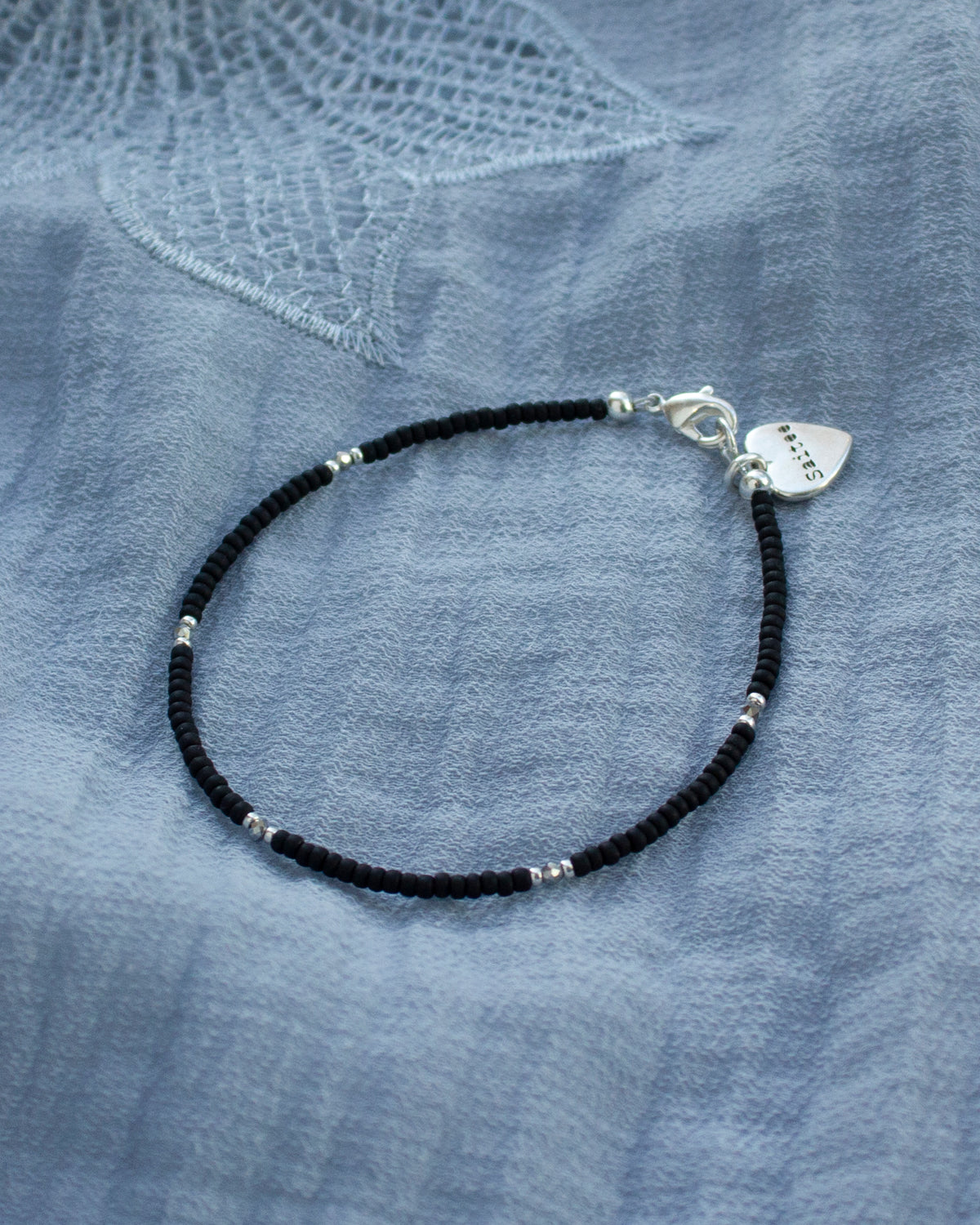 fijn mat zwart kralenarmbandje met hartjesbedel