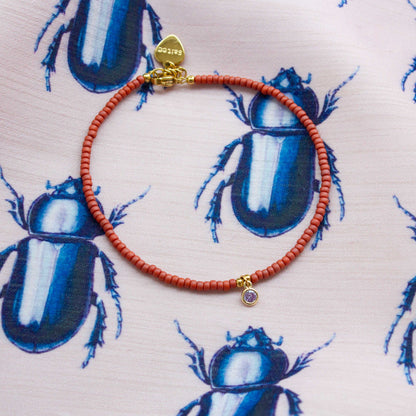 close up terra rood enkelbandje met bedel 