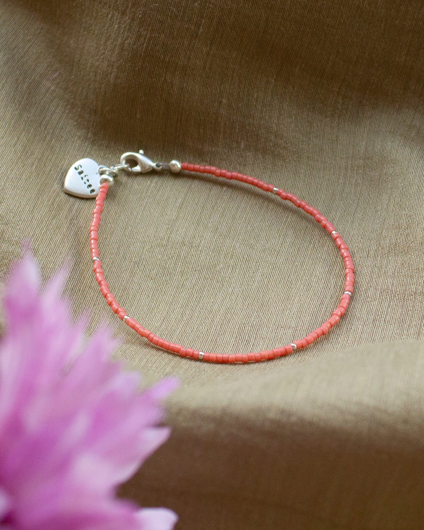 fijn oranjeroze kralenarmbandje met hartjesbedel