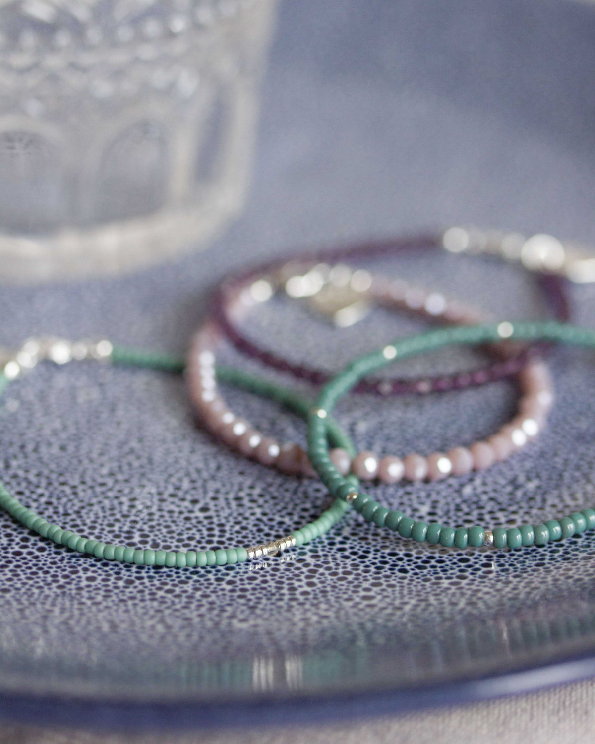 armbandensetje op blauw bord in lila en groen tinten