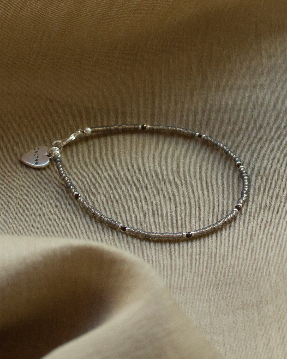 fijn grijsbruin kralenarmbandje met hartjesbedel